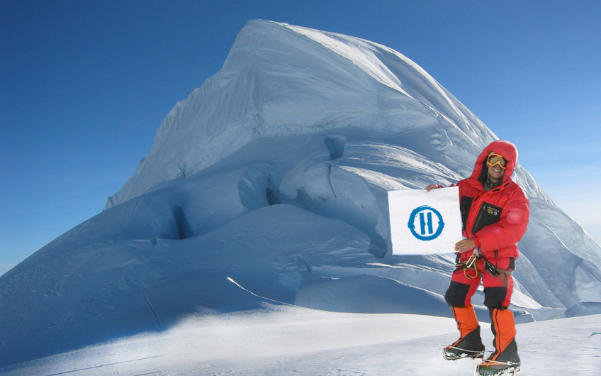 man on mountain summit with Heroik flag