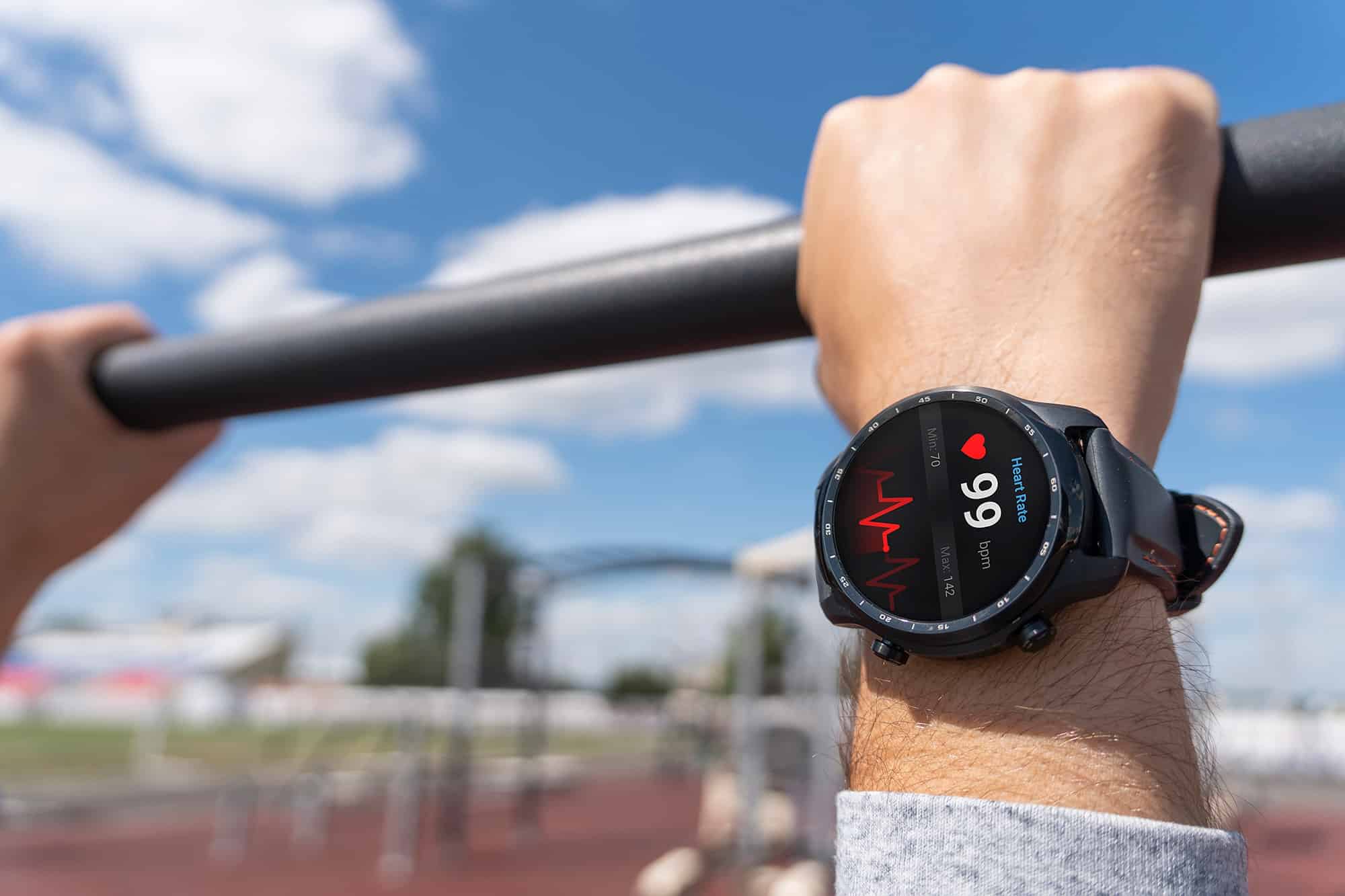 man holding pull up bar with smartwatch in focus