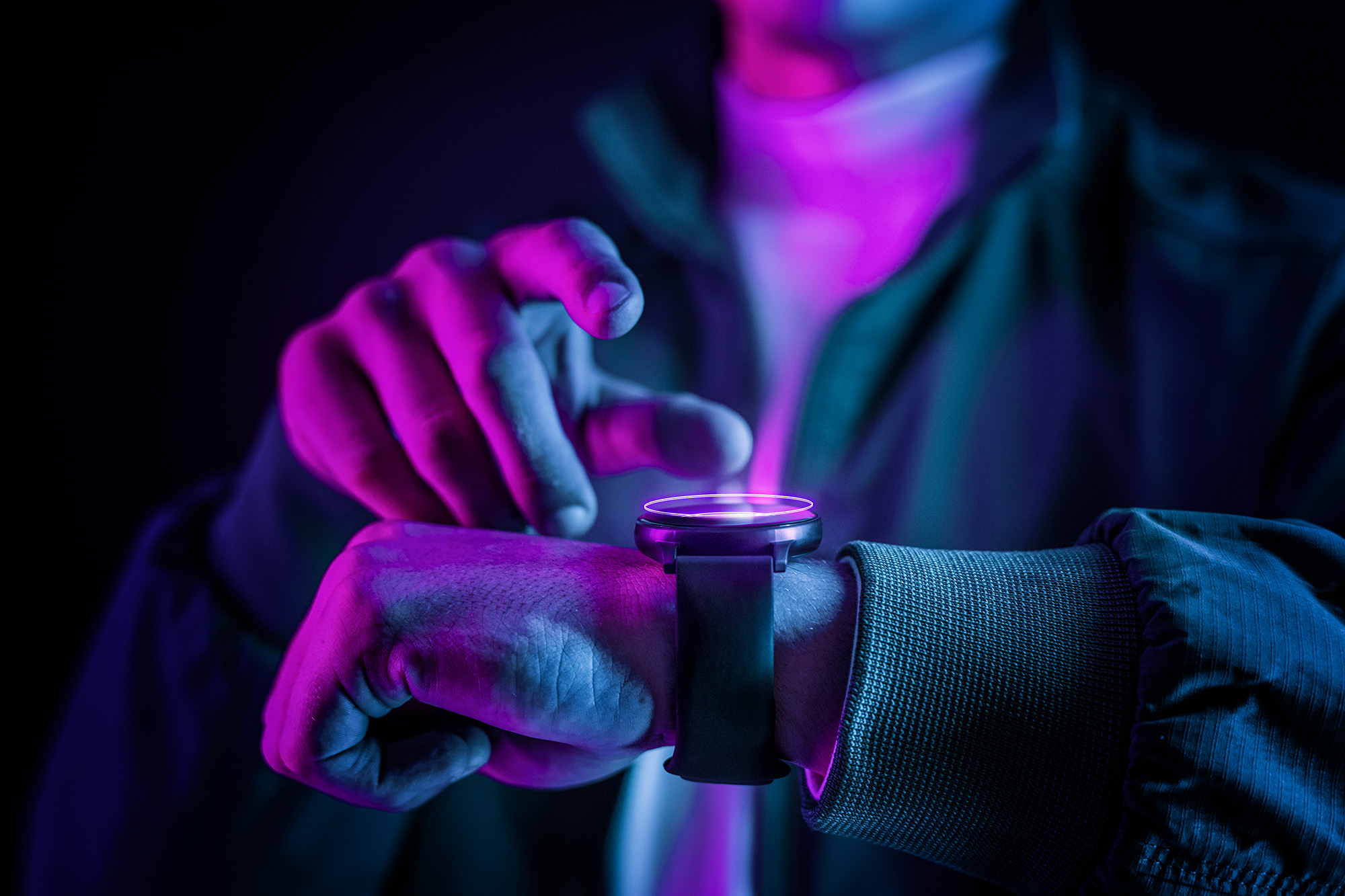 purple and pink lighting of man with smart watch close up